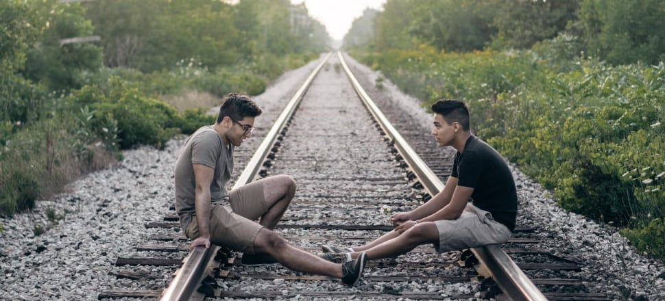 Two friends sitting talking on a railroad track