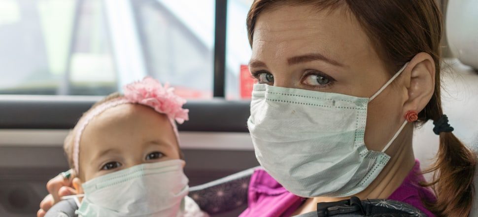 mother and daughter wearing pollution protection masks in taxi